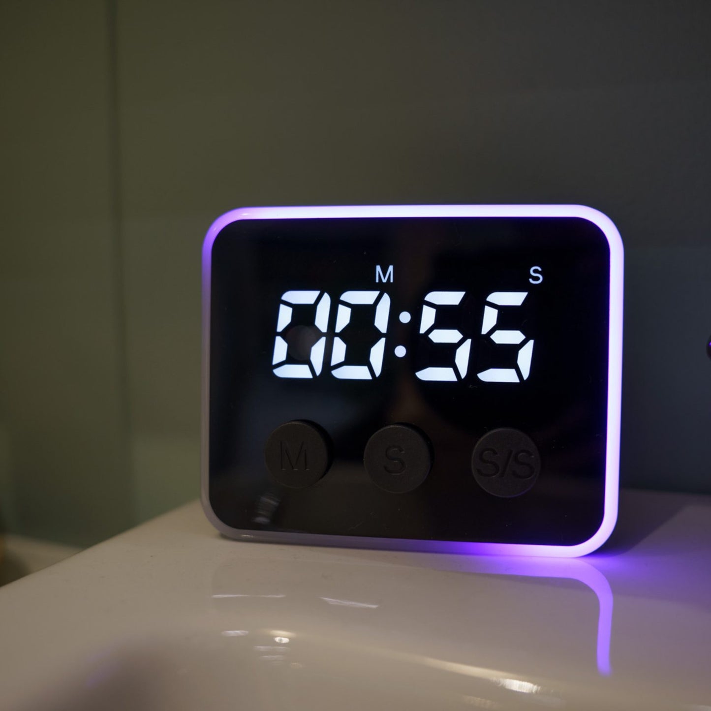 Looptimer visual timer with purple LED light counting 55 seconds on a glossy bathroom counter