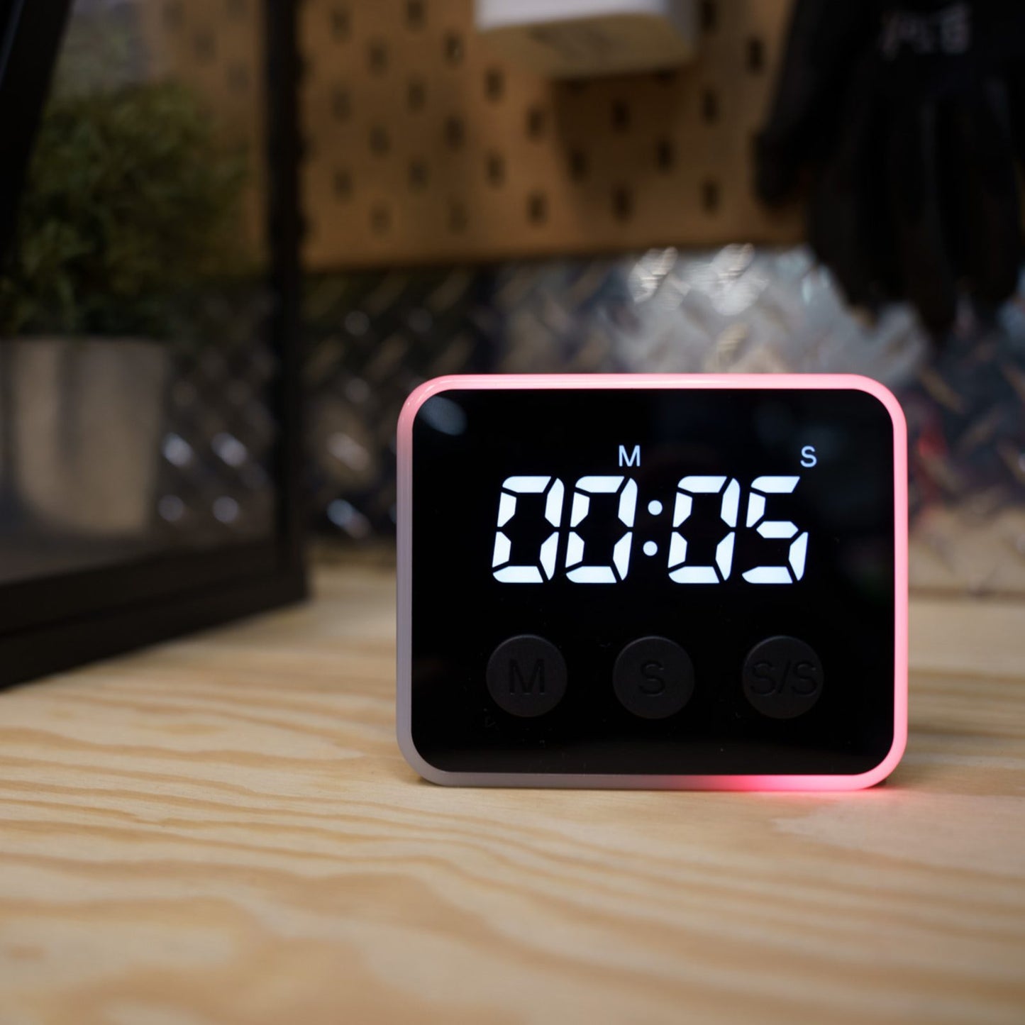 Looptimer visual timer glowing red with 5 seconds remaining on a workshop bench with pegboard tools behind
